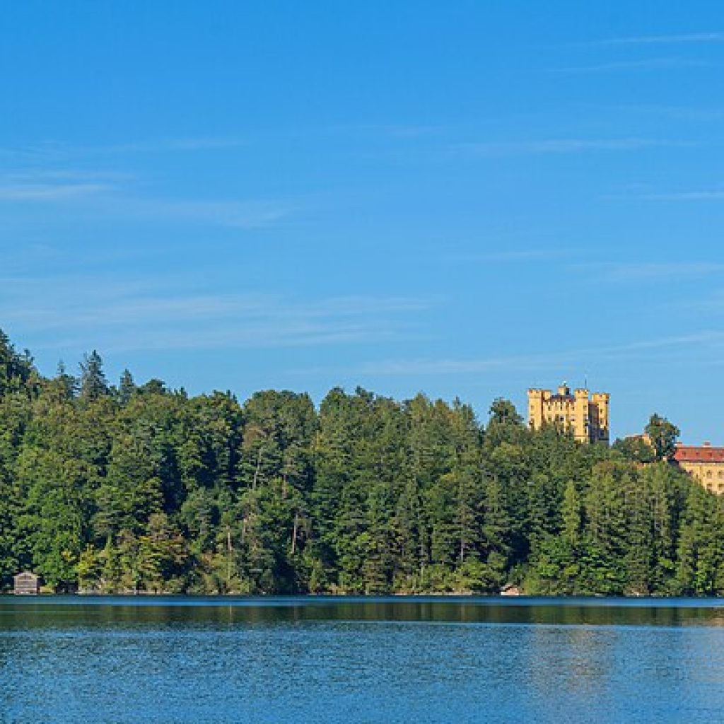 Almanya'daki Neuschwanstein Şatosu'nun Alpsee Gölü ve çevresindeki ormanla birlikte görünümü