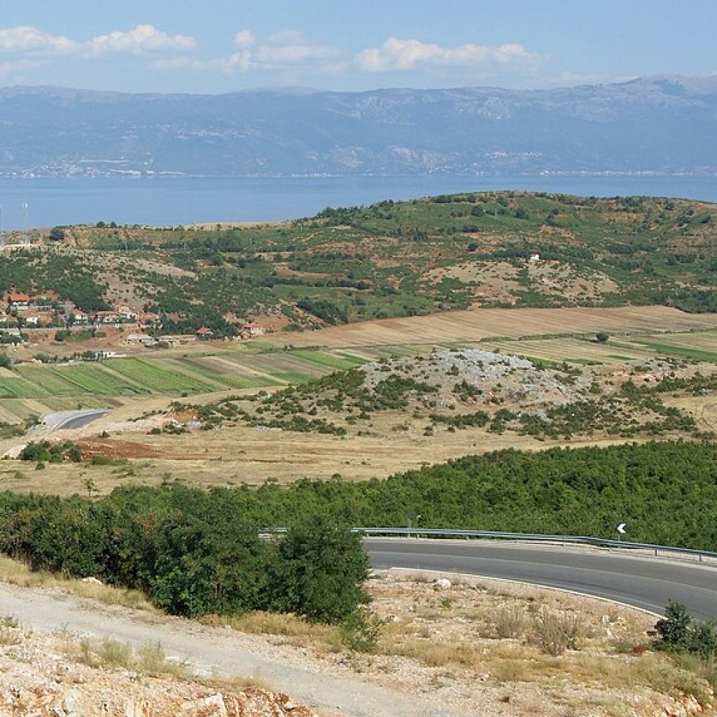 Kuzey Makedonya sınırındaki Ohrid Gölü'nün dağlarla çevrili berrak su yüzeyinin görünümü