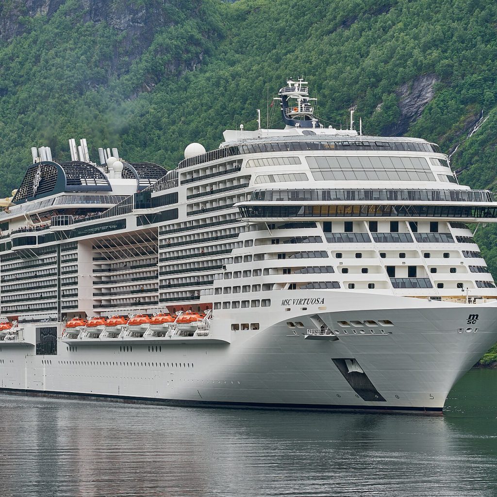 Norveç'teki Geiranger Fiyordu'nda ilerleyen büyük bir gemi ile çevresindeki sarp kayalıkların görünümü